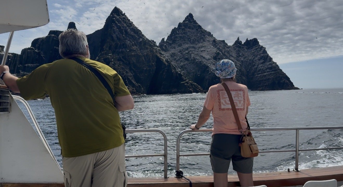 Passengers at the rail beneath the Skellig rocks